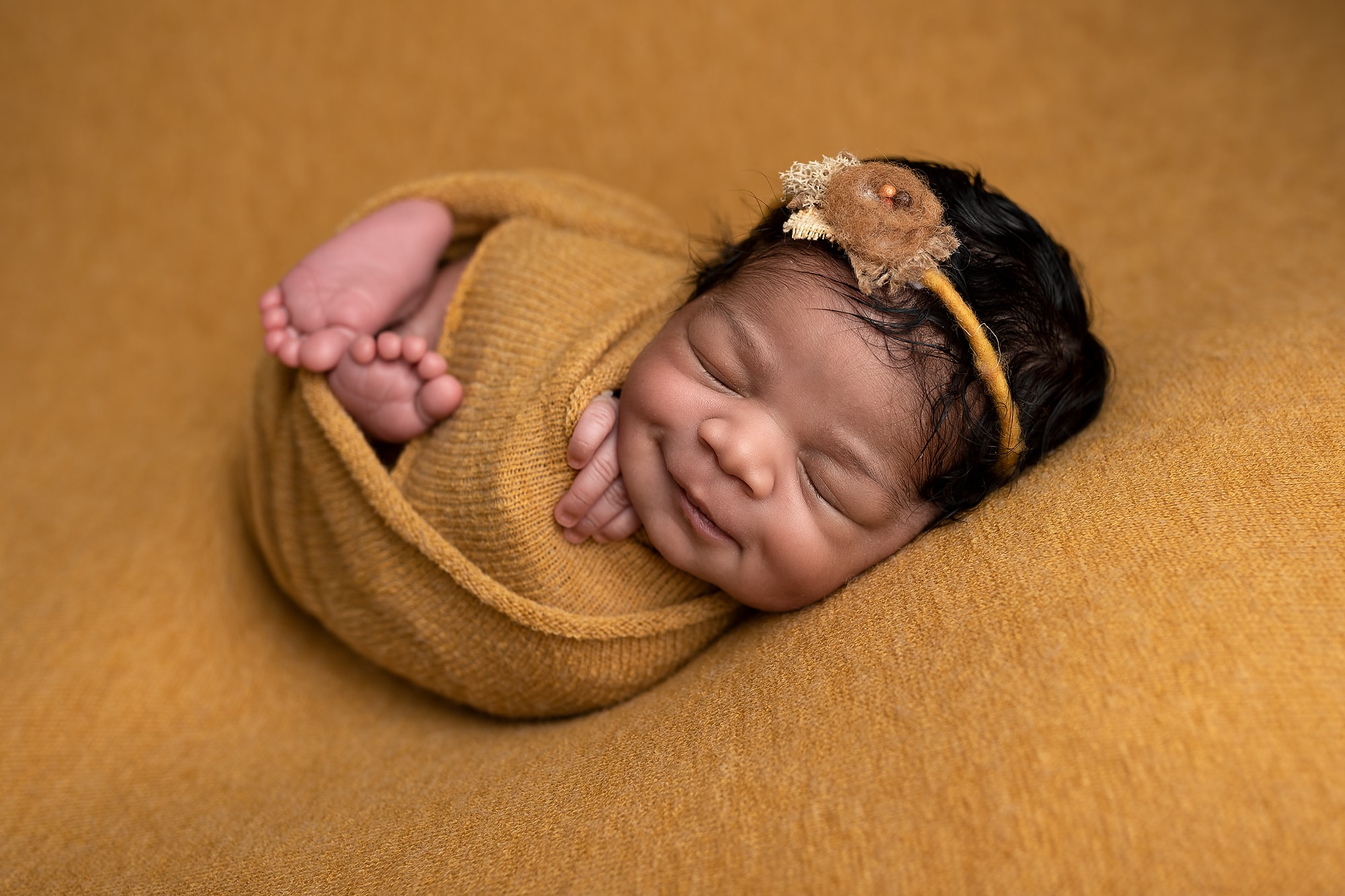 Sleeping Newborn Baby Girl Smilling, Wrapped in Mustard Coloured Wrap