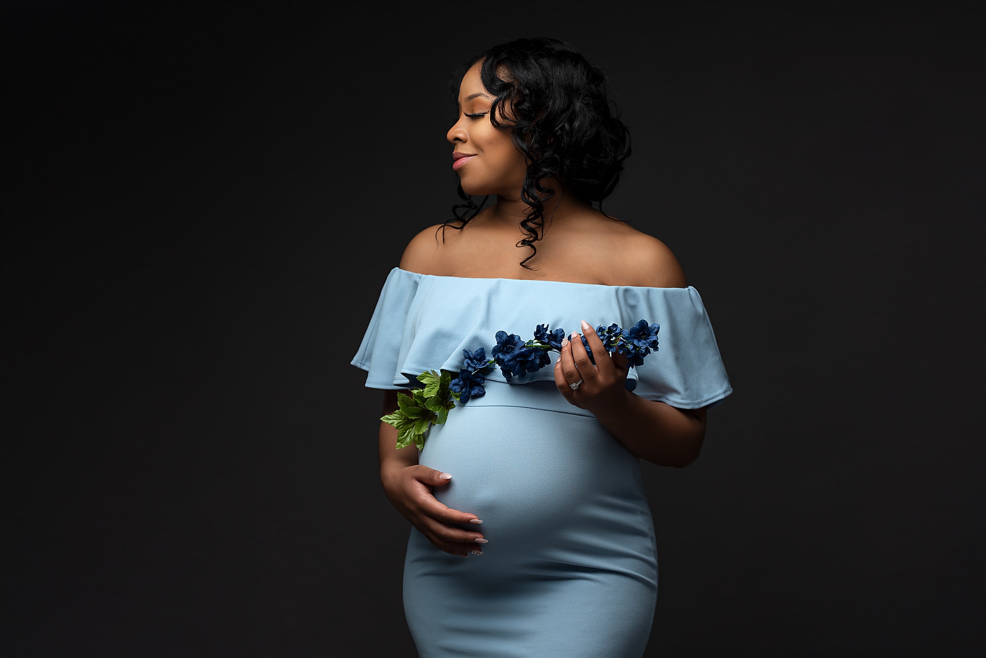 Maternity Photograph Pregnant Woman in a Blue Dress holding Blue Flowers